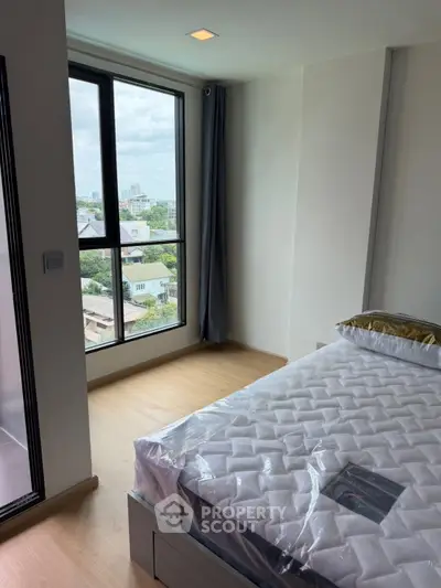 Bright bedroom with large window offering stunning city views and modern decor.