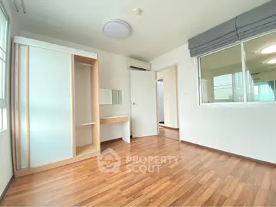 Spacious empty bedroom with wooden flooring and built-in wardrobe in modern apartment.