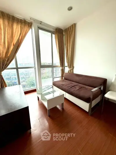 Bright living room with large windows and modern furniture in a high-rise apartment.