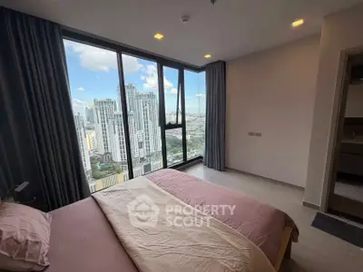 Modern bedroom with stunning city view and floor-to-ceiling windows in a high-rise apartment.