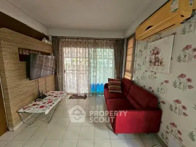 Cozy living room with red sofa, wall-mounted TV, and floral wallpaper