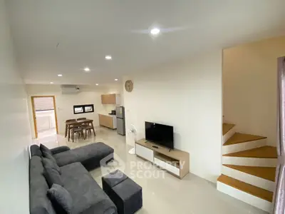 Spacious modern living room with sleek furniture and open kitchen layout in a contemporary home.