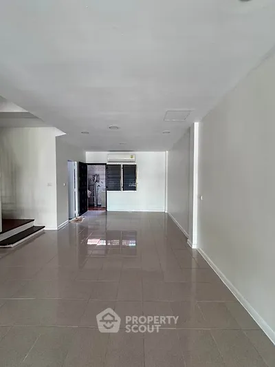 Spacious empty living room with tiled floor and air conditioning, ready for customization.