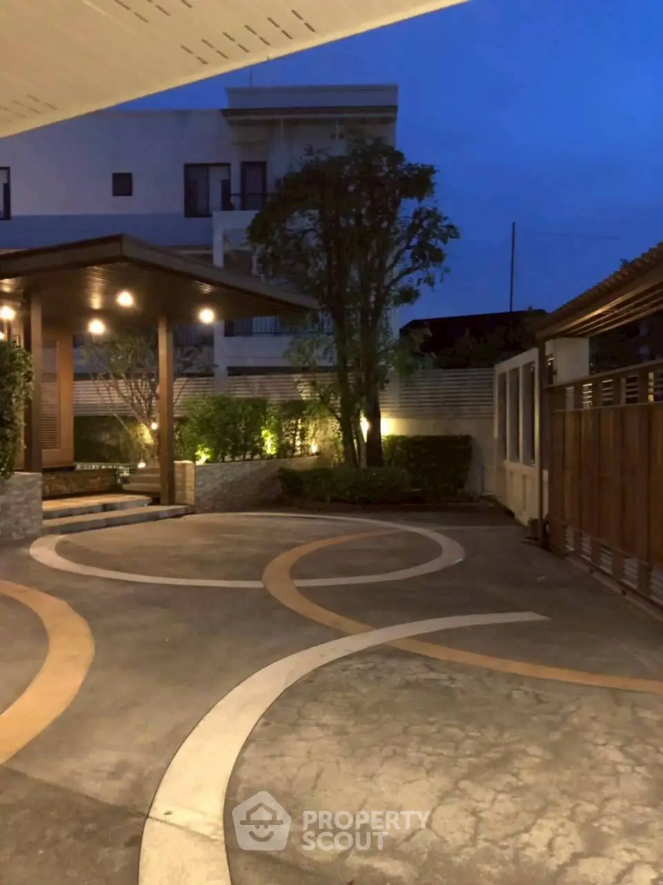 Elegant evening view of a modern building entrance with stylish lighting and landscaping.
