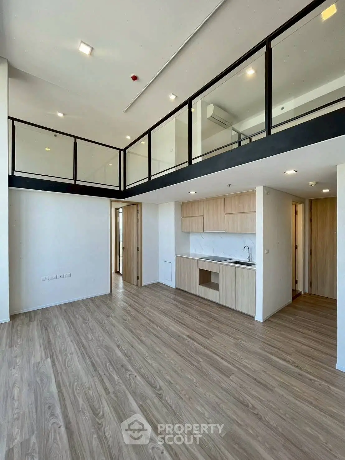 Modern loft apartment with open kitchen and mezzanine level, featuring sleek wood flooring and minimalist design.
