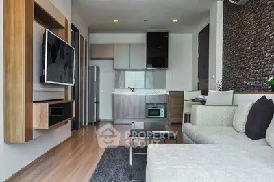 Modern living room with sleek kitchen, featuring open layout and stylish decor.