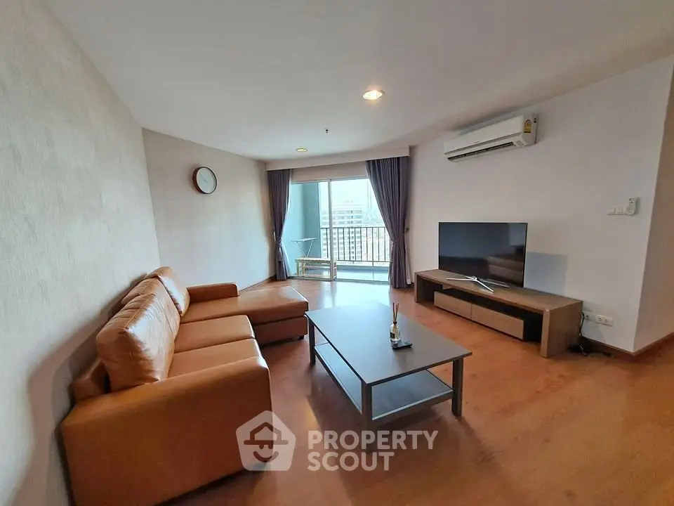 Spacious living room with modern furniture and balcony view in urban apartment.