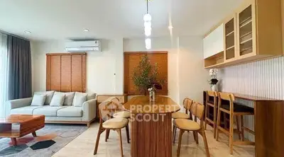 Stylish modern living room with dining area, featuring elegant furniture and warm lighting.