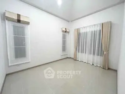 Spacious empty room with large windows and elegant curtains, perfect for customization.