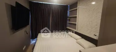 Cozy bedroom with modern design and wall-mounted TV, perfect for relaxation.