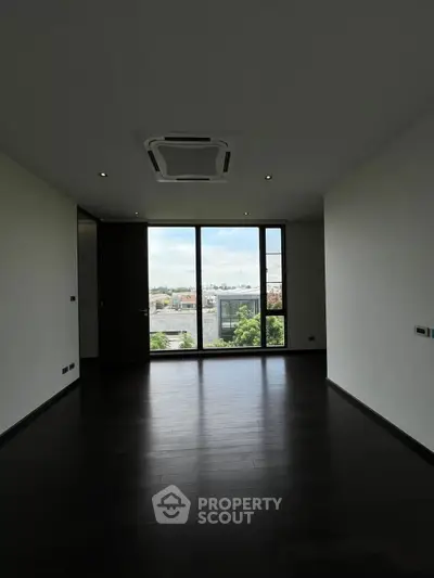 Spacious room with large window offering stunning city view, perfect for modern living.