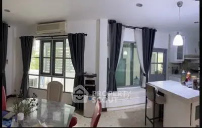 Spacious modern kitchen with island and dining area, featuring large windows and stylish decor.