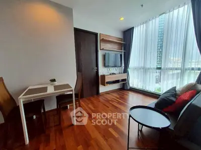 Modern living room with hardwood floors and large windows in a high-rise apartment.