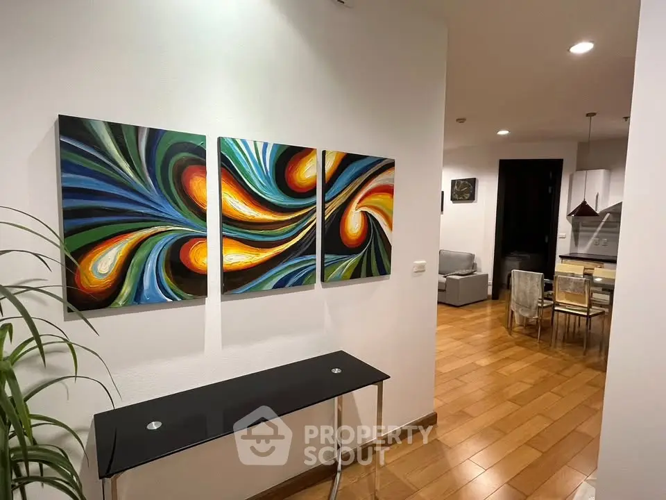 Modern apartment interior with vibrant artwork and open layout, featuring stylish dining and living areas.