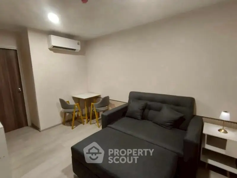 Cozy living room with modern sofa and dining area in compact apartment.