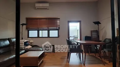 Modern living room with stylish furniture and wooden flooring, featuring a cozy seating area and dining table.