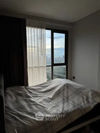 Cozy bedroom with a stunning city view through large windows, perfect for urban living.