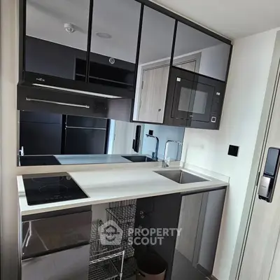 Modern compact kitchen with sleek cabinetry and built-in appliances in a stylish apartment.