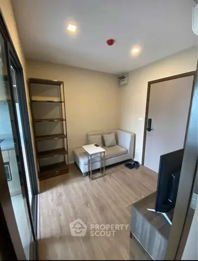 Cozy living room with modern furniture and wooden flooring in a compact apartment.