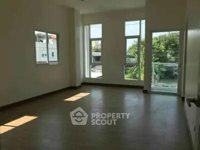 Spacious room with large windows offering natural light and street view.