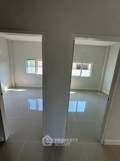 Bright and spacious empty rooms with glossy tiled floors and large windows.