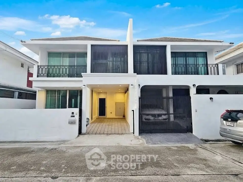Modern white two-story house with spacious driveway and sleek design