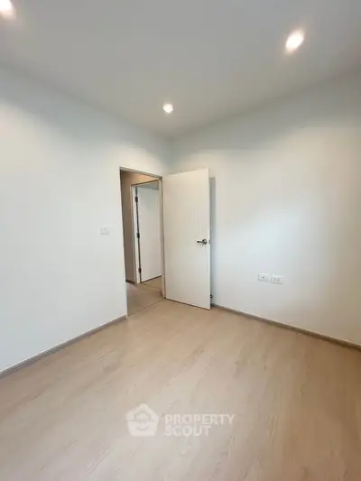 Spacious empty bedroom with wooden flooring and modern lighting, perfect for customization.