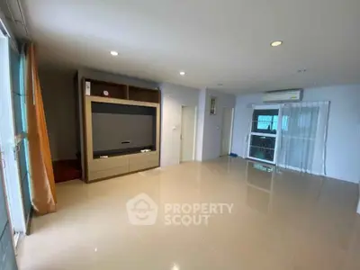 Spacious living room with modern entertainment unit and large windows for natural light.