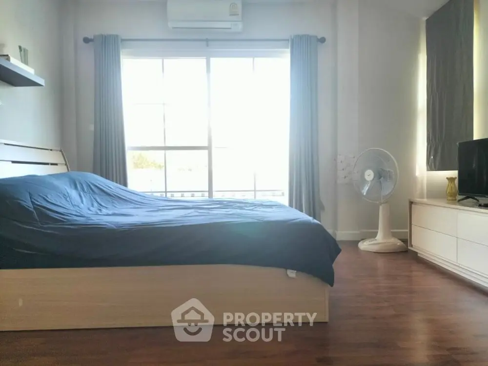 Spacious bedroom with large window and modern furnishings, ideal for comfort and relaxation.