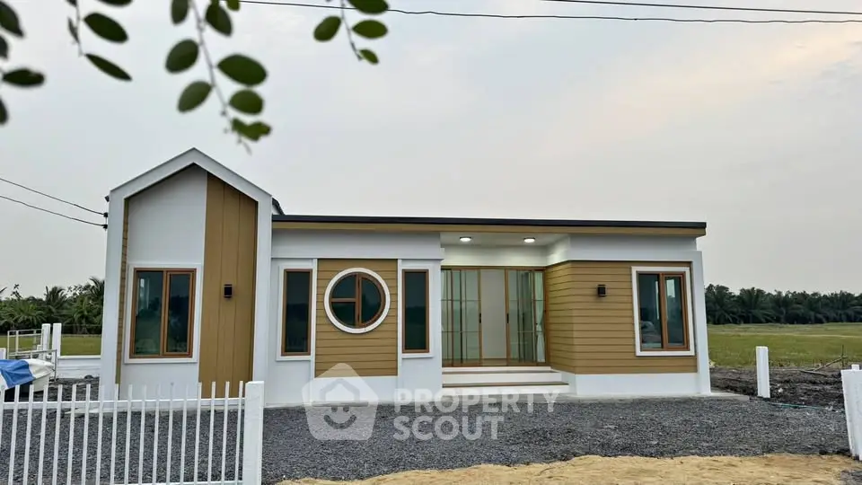 Modern single-story house with unique circular window and stylish facade in serene countryside setting.