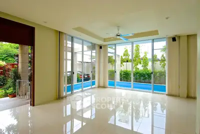Spacious living room with large windows and pool view, perfect for modern living.