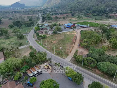 Scenic aerial view of countryside road with lush greenery and distant mountains, ideal for real estate development.