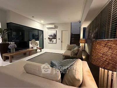 Modern living room with stylish decor and ambient lighting, featuring a cozy seating area and contemporary artwork.