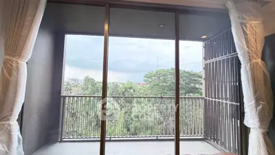 Spacious balcony with stunning green view through large glass doors, perfect for relaxation.