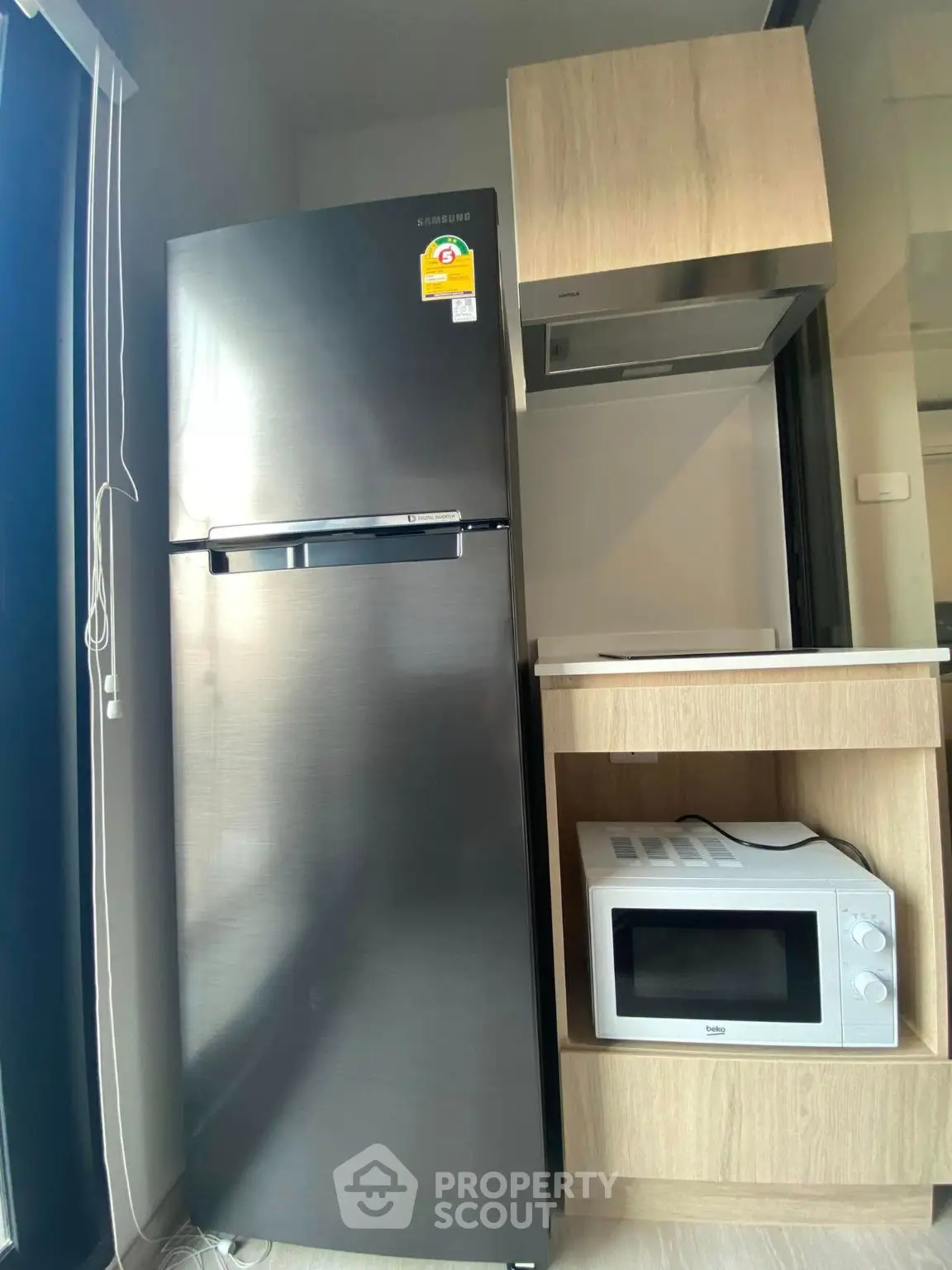 Modern kitchen with sleek stainless steel fridge and microwave in compact layout.