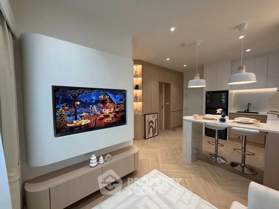 Modern open-layout living room with stylish kitchen and mounted TV, featuring elegant decor and lighting.
