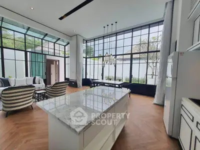 Luxurious open-plan living area with modern kitchen and elegant dining space, featuring floor-to-ceiling windows.