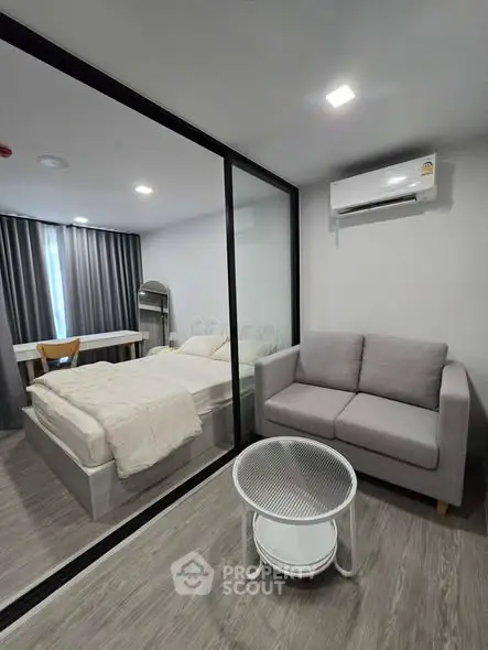 Modern studio apartment with glass partition, cozy sofa, and air conditioning.