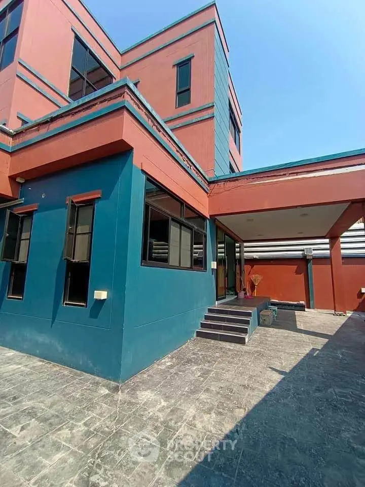 Modern multi-story building with vibrant colors and spacious outdoor area.