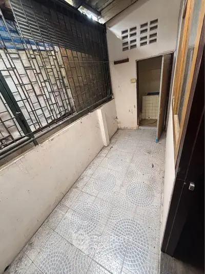 Compact balcony with tiled floor and partial roof cover, ideal for small outdoor setup.