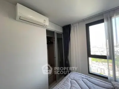Modern bedroom with air conditioning and city view, featuring a cozy bed and ample natural light.
