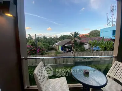 Charming balcony with outdoor seating and scenic view of lush greenery and neighborhood.