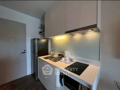 Modern kitchen with sleek cabinetry, induction cooktop, and stainless steel fridge in a compact layout.