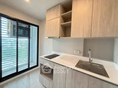 Modern kitchen with sleek cabinetry and balcony view in a stylish apartment.