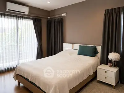 Cozy bedroom with modern decor, featuring a comfortable bed and natural light from large windows.