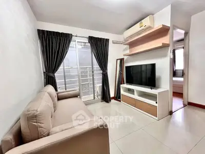 Modern living room with sleek sofa, TV, and balcony access in stylish apartment.