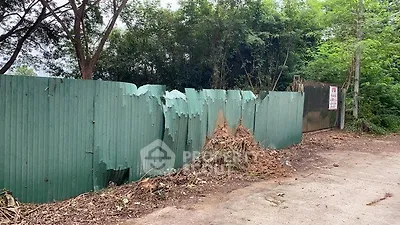 Damaged green fence with trees and foliage in a real estate setting