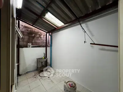 Spacious utility area with metal roof and tiled flooring, ideal for laundry or storage.