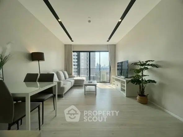Spacious modern living room with large windows and city view, featuring sleek furniture and elegant decor.
