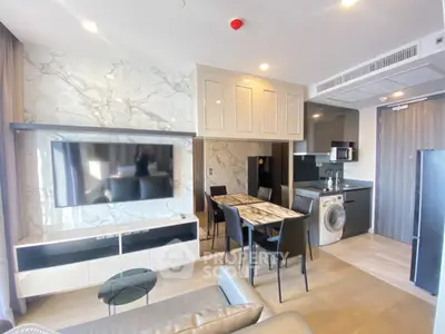Modern living room with marble accents, sleek kitchen, and integrated appliances in a stylish apartment.